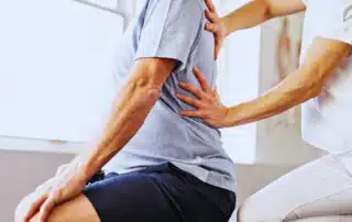 physical therapist guiding a patient through posture correction exercises to reduce back and neck pain from poor alignment habits